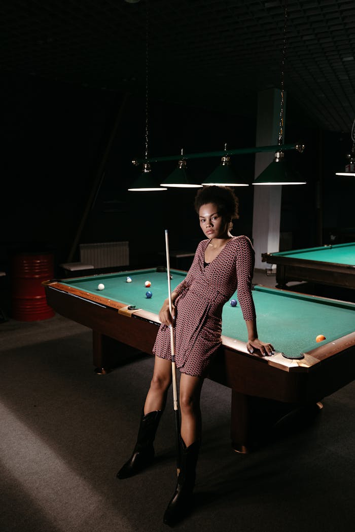 Woman Standing Beside Billiard Table While Holding a Cue Stick